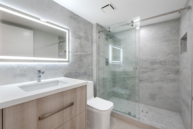 bathroom featuring walk in shower, vanity, toilet, and tile walls