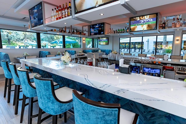 bar with light stone counters and hardwood / wood-style floors