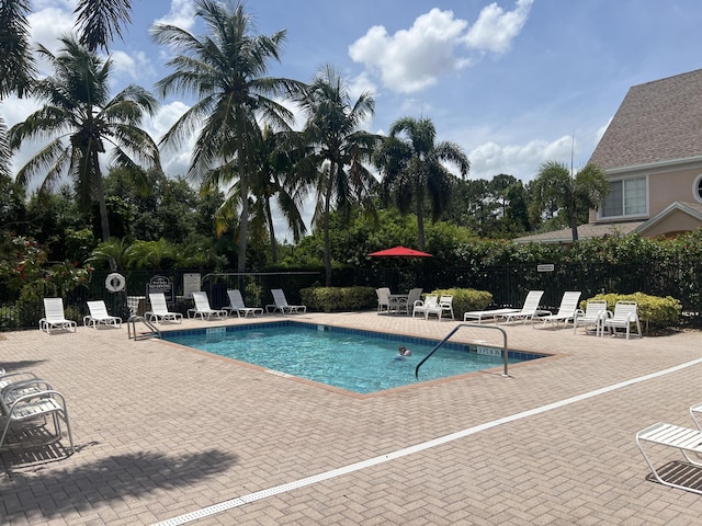 community pool with a patio area and fence