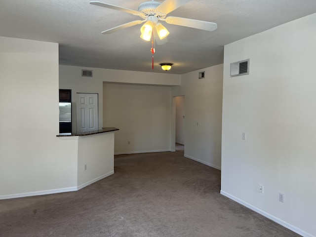 carpeted spare room with baseboards, visible vents, and a ceiling fan