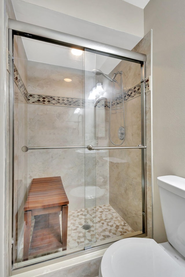 bathroom with a shower with door and toilet