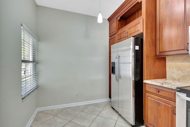 kitchen with light stone countertops, stainless steel appliances, backsplash, decorative light fixtures, and light tile patterned floors