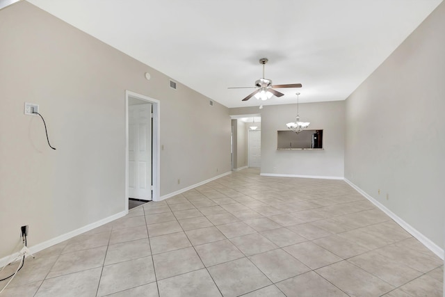 tiled spare room featuring ceiling fan with notable chandelier