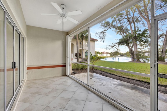 unfurnished sunroom with ceiling fan and a water view