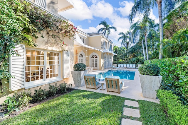 view of swimming pool featuring french doors, a patio, and a lawn