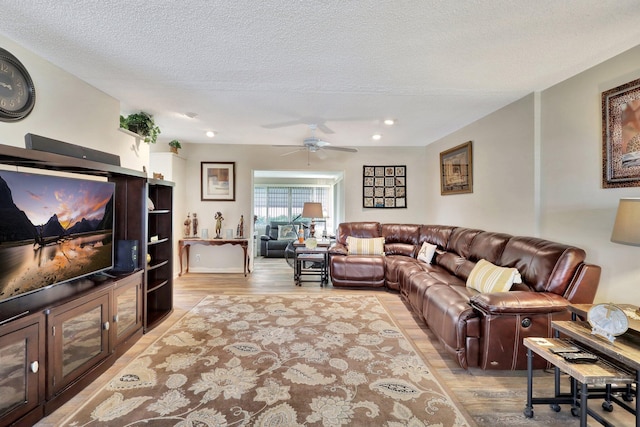 living room with ceiling fan, light hardwood / wood-style floors, and a textured ceiling