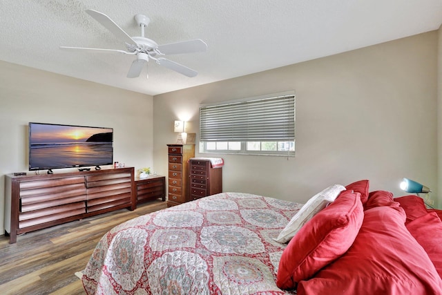 bedroom with a textured ceiling, hardwood / wood-style flooring, and ceiling fan