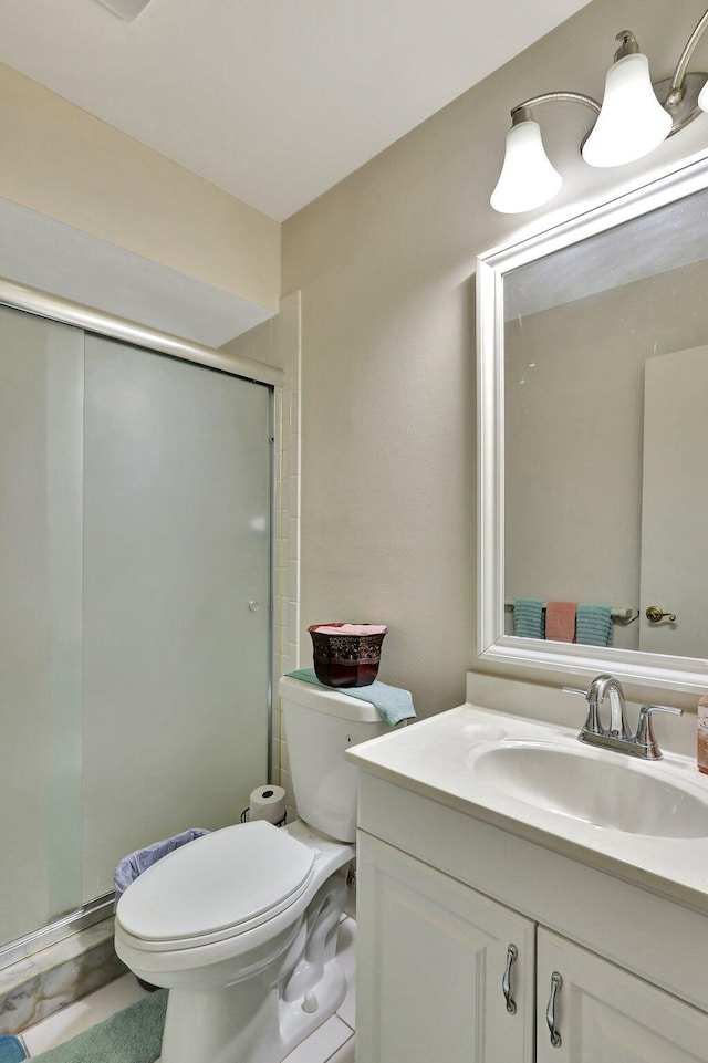 bathroom with tile patterned floors, vanity, an enclosed shower, and toilet