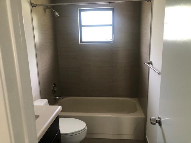 full bathroom featuring tiled shower / bath, vanity, and toilet