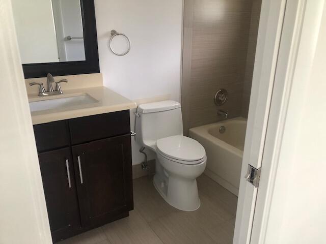 full bathroom with vanity, tiled shower / bath combo, and toilet