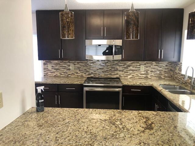 kitchen with appliances with stainless steel finishes, tasteful backsplash, dark brown cabinets, and sink