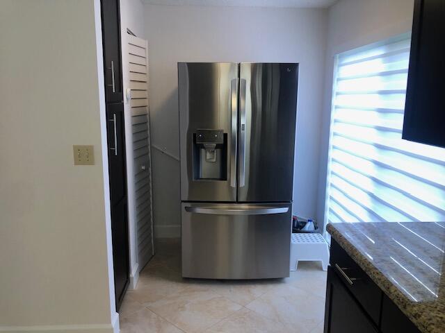 kitchen with stone countertops and stainless steel refrigerator with ice dispenser