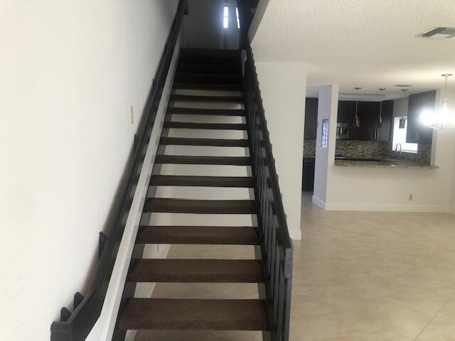 stairs featuring a textured ceiling and a notable chandelier