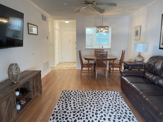 living room with ceiling fan, ornamental molding, and light hardwood / wood-style flooring