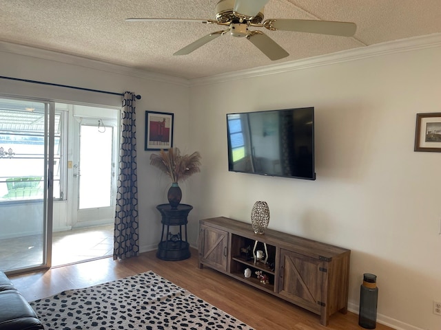 living room with a textured ceiling, ceiling fan, light wood-type flooring, and ornamental molding