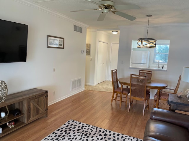 dining area with ceiling fan with notable chandelier, light hardwood / wood-style floors, and ornamental molding