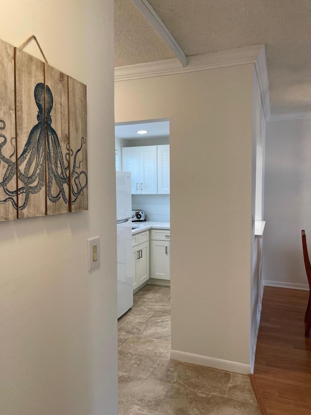 hallway featuring crown molding, a textured ceiling, and light wood-type flooring