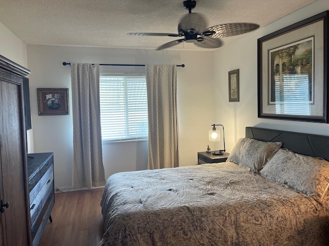 bedroom with ceiling fan, dark hardwood / wood-style flooring, and a textured ceiling