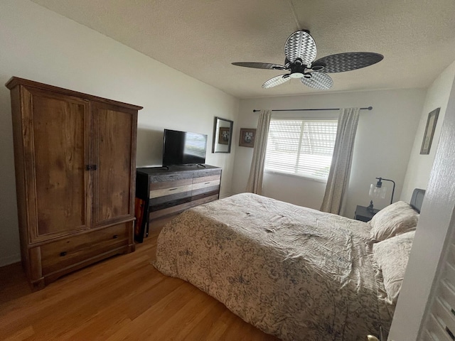 bedroom featuring ceiling fan, wood-type flooring, and a textured ceiling