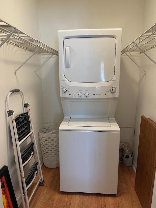 laundry area with light hardwood / wood-style flooring and stacked washer / drying machine