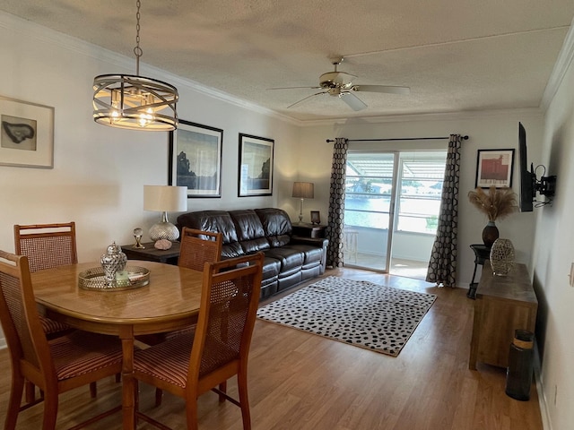 dining area featuring ceiling fan with notable chandelier, wood-type flooring, ornamental molding, and a textured ceiling