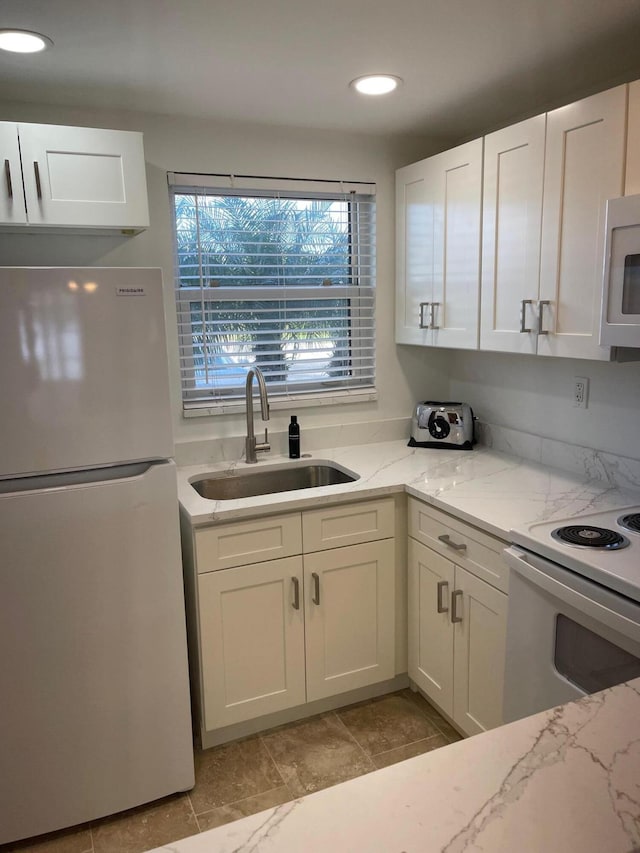 kitchen with white cabinetry, sink, light stone counters, and white appliances