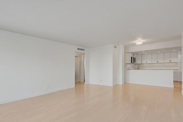 unfurnished living room with light wood-type flooring and sink