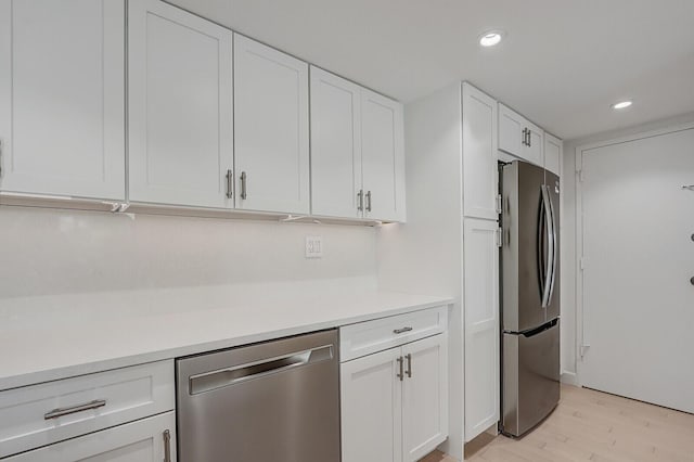 kitchen featuring appliances with stainless steel finishes, light wood-type flooring, and white cabinetry