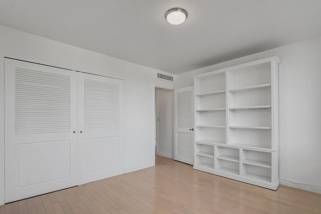 unfurnished bedroom with light wood-type flooring and a closet