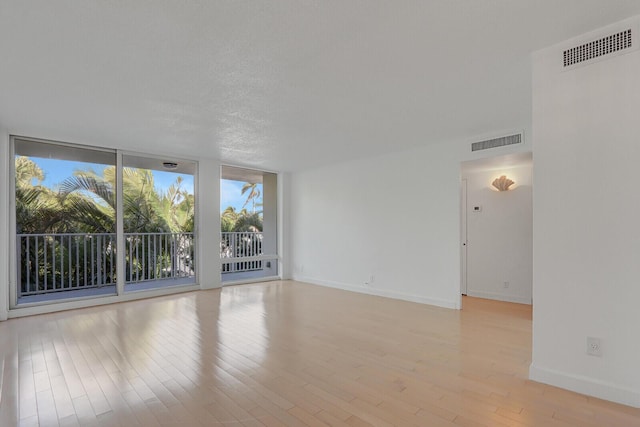 unfurnished room with light hardwood / wood-style floors and a textured ceiling