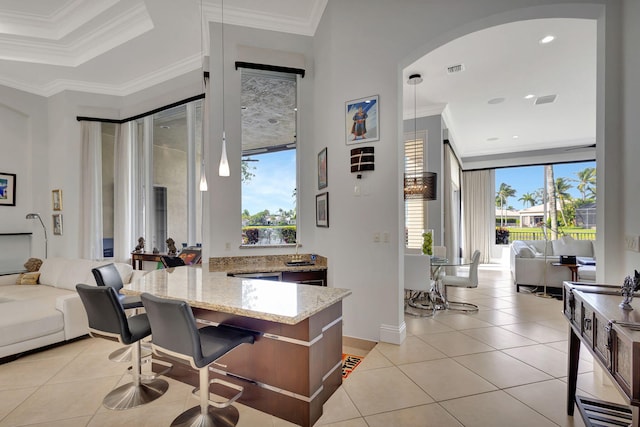 kitchen with light tile patterned floors, light stone counters, plenty of natural light, and crown molding