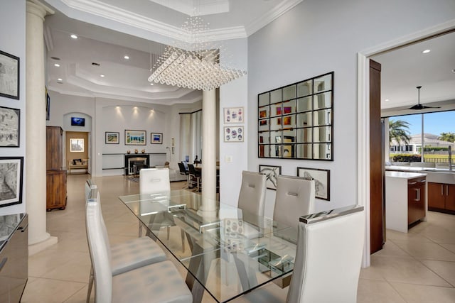 dining space featuring decorative columns, ornamental molding, a raised ceiling, light tile patterned floors, and an inviting chandelier