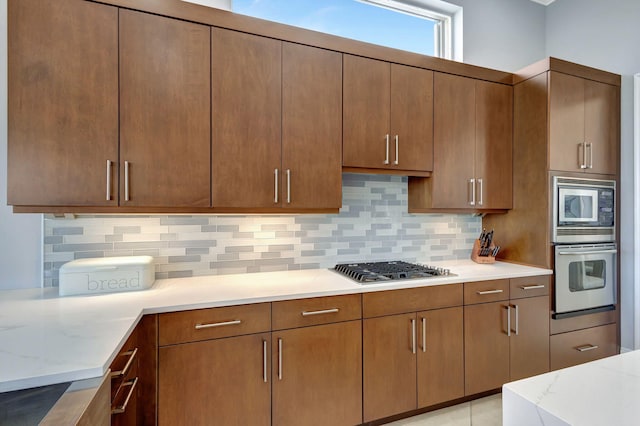 kitchen with light stone countertops, backsplash, and appliances with stainless steel finishes