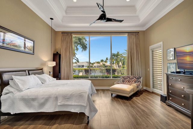 bedroom with access to exterior, hardwood / wood-style floors, a raised ceiling, and ornamental molding