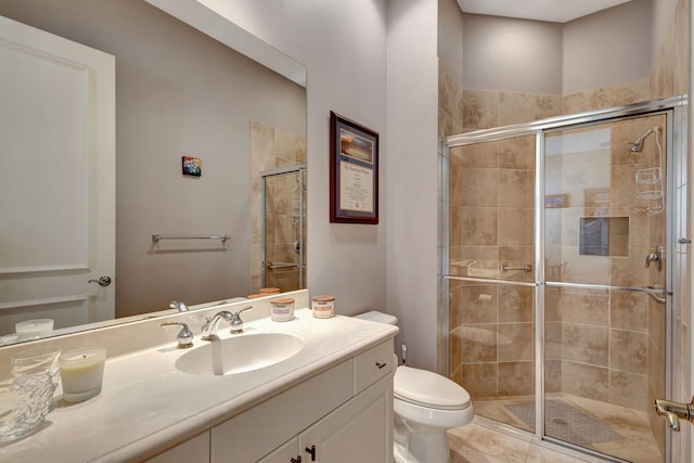 bathroom featuring tile patterned floors, vanity, toilet, and a shower with shower door