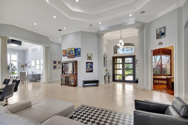 living room featuring french doors, a towering ceiling, light wood-type flooring, ornamental molding, and an inviting chandelier