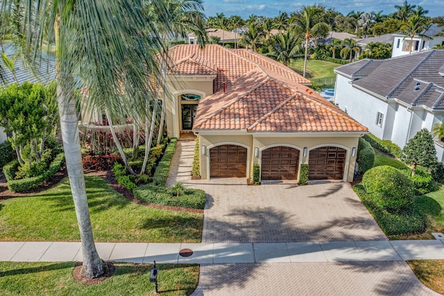 mediterranean / spanish-style house with a garage and a front lawn