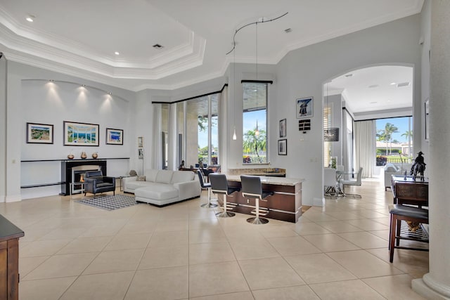 living room with a healthy amount of sunlight, a raised ceiling, light tile patterned floors, and crown molding