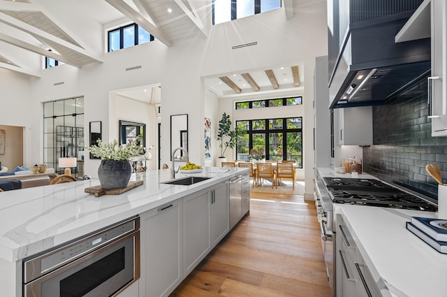 321 NW 7th St, Delray Beach, FL 33444 - kitchen with appliances with stainless steel finishes, a high ceiling, wall chimney exhaust hood, open floor plan, and light wood-style floors