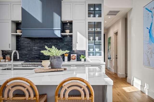 321 NW 7th St, Delray Beach, FL 33444 - kitchen with open shelves, decorative backsplash, light wood-type flooring, and wall chimney exhaust hood