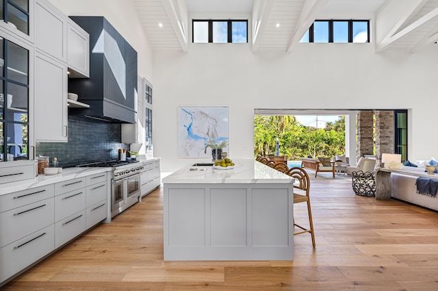321 NW 7th St, Delray Beach, FL 33444 - kitchen with range with two ovens, light stone countertops, an island with sink, a high ceiling, and open floor plan