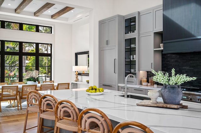 321 NW 7th St, Delray Beach, FL 33444 - kitchen featuring gray cabinets, a towering ceiling, a breakfast bar area, beamed ceiling, and light wood finished floors