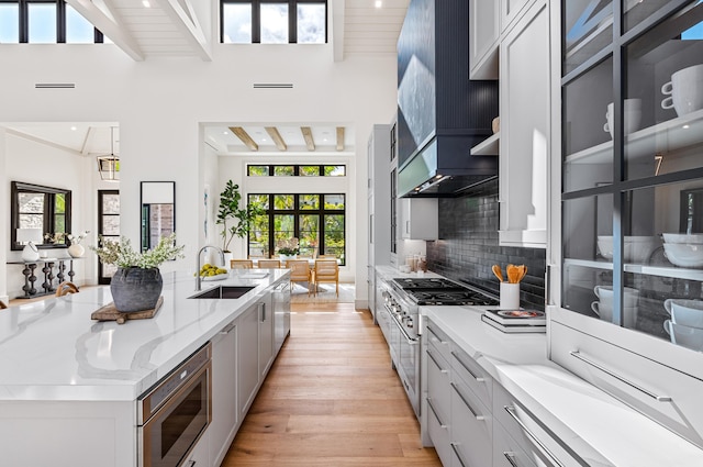 321 NW 7th St, Delray Beach, FL 33444 - kitchen with appliances with stainless steel finishes, light wood finished floors, a large island with sink, light stone countertops, and backsplash
