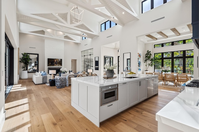 321 NW 7th St, Delray Beach, FL 33444 - kitchen with high vaulted ceiling, stainless steel dishwasher, a kitchen island with sink, light wood-style flooring, and beam ceiling