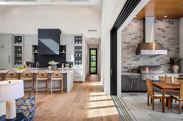 321 NW 7th St, Delray Beach, FL 33444 - kitchen with wall chimney exhaust hood, light countertops, a towering ceiling, backsplash, and a kitchen breakfast bar