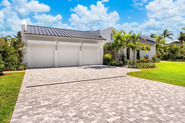 321 NW 7th St, Delray Beach, FL 33444 - view of front of house with decorative driveway, a front lawn, stucco siding, an attached garage, and a metal roof
