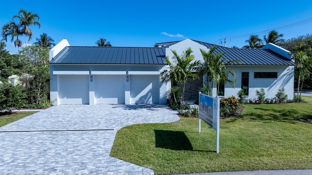 321 NW 7th St, Delray Beach, FL 33444 - view of front facade with a metal roof, decorative driveway, a front lawn, an attached garage, and stucco siding