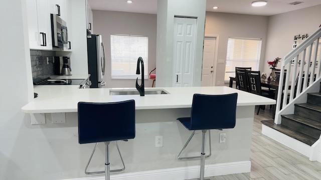 kitchen featuring a breakfast bar, sink, kitchen peninsula, and stainless steel appliances