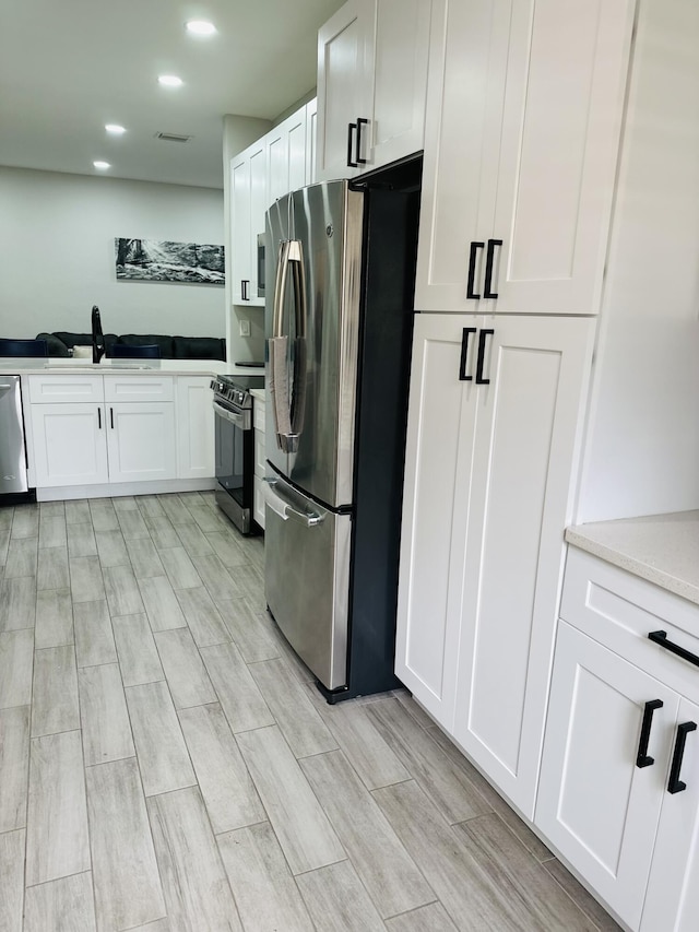 kitchen featuring white cabinetry, sink, stainless steel appliances, and light wood-type flooring