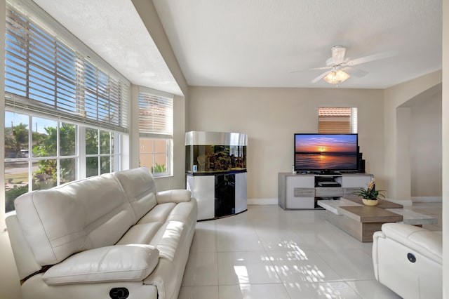 living room featuring ceiling fan, a textured ceiling, and light tile patterned floors